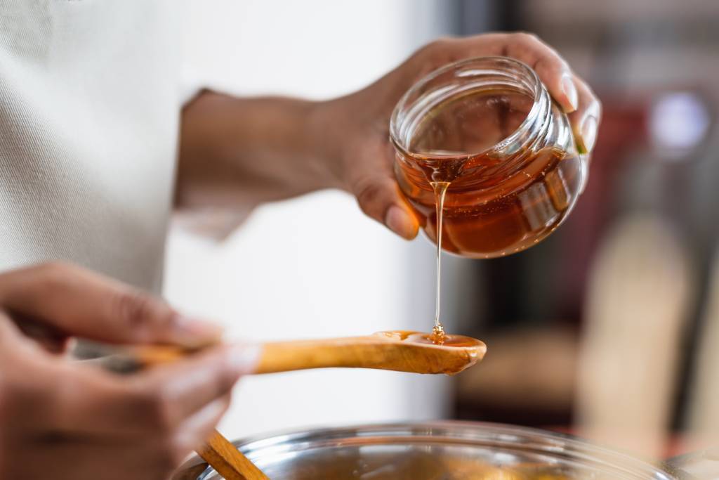 A chef holds a jar of hand-collected honey while preparing a recipe.