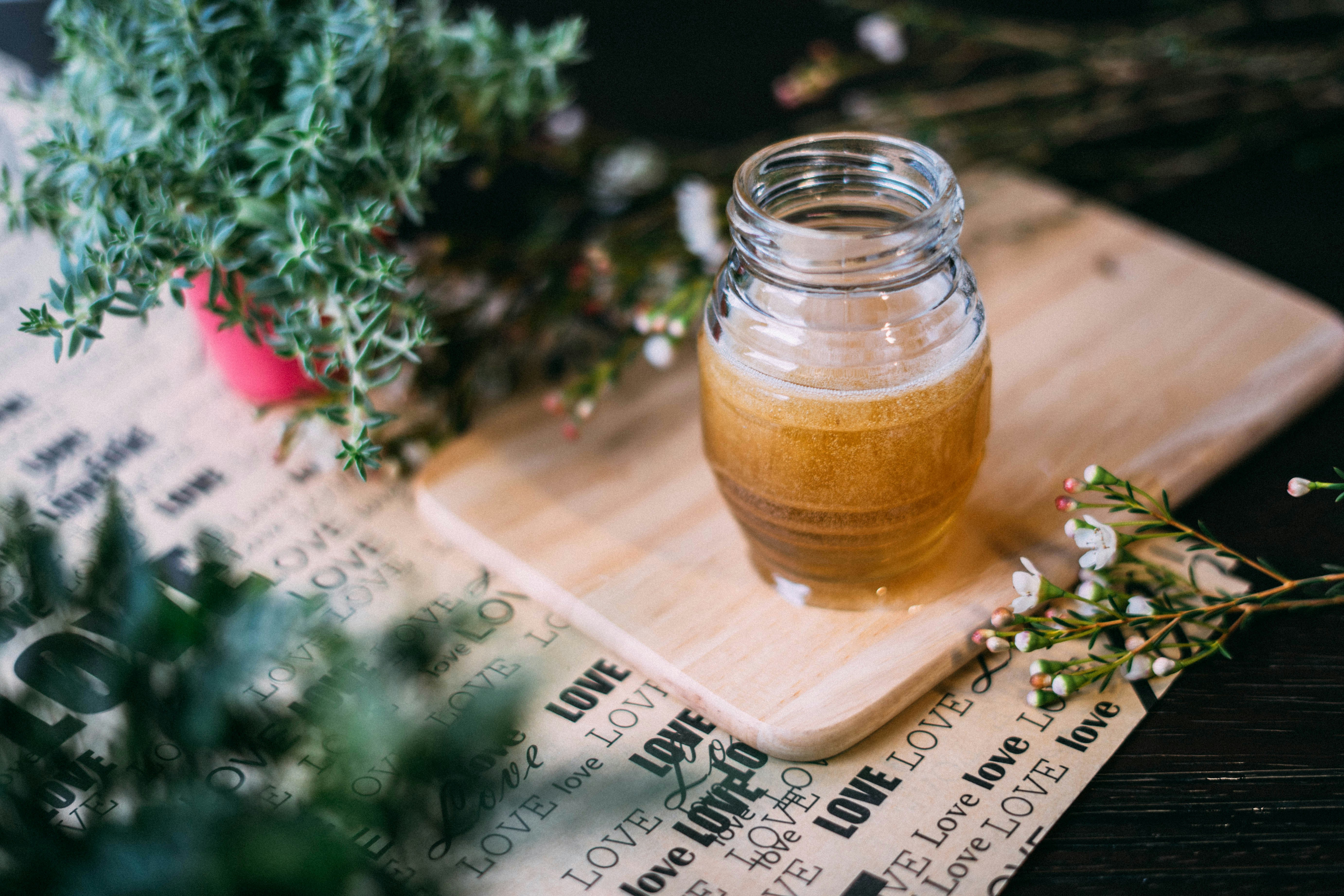 Jar of raw honey on wooden cutting board